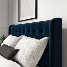 a blue headboard with two white pillows on it and a black framed picture above