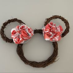 a mickey mouse head made out of flowers on a wreath with some branches around it