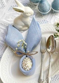 a white plate topped with an egg and bunny napkin holder next to utensils