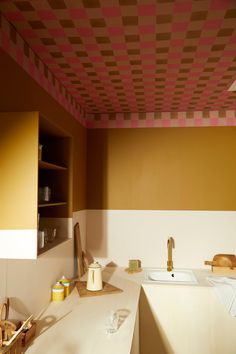 a kitchen area with counter, sink and cabinets in it's center space that is painted yellow and pink