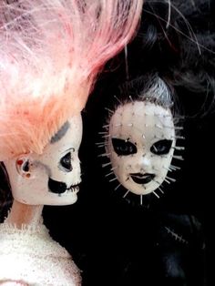 two dolls with white and black makeup are facing each other