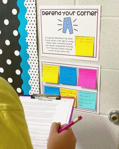 a person holding a pen and writing on a piece of paper with sticky notes attached to it