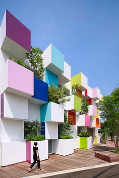 a person riding a bike in front of a building with colorful blocks on the side