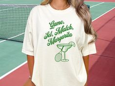 Introducing our Comfort Colors Tennis Shirt with the Funny saying "Game, Set, Match, Margarita" - the perfect blend of style and sass for the trendy tennis player!  Crafted with the utmost care, this Unisex Graphic Tshirt is made from premium Comfort Colors fabric, ensuring a soft, cozy feel that keeps you comfortable throughout your game. Whether you're hitting the courts for a fierce match or simply want to flaunt your love for tennis in style, this Tennis Shirt is your go-to choice.  Made with 100% with ring-spun cotton, this soft-washed, garment-dyed fabric brings extra coziness to your wardrobe while the relaxed fit makes it an excellent daily choice. The double-needle stitching throughout the tee makes it highly durable while the lack of side-seams helps the shirt retain its tubular Tennis Graphic, Game Set Match, Tennis Shirt, Tennis Gifts, Tennis Shirts, Tennis Player, Retro Tshirt, Tennis Players, Dyed Fabric