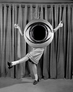 a woman is standing in front of a curtain with an eyeball on her head