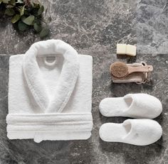 a white robe, slippers and comb are laid out on a marble countertop