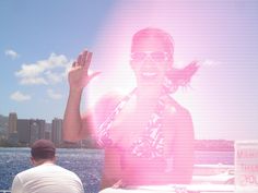 a man and woman sitting on a boat in front of the ocean with their hands up