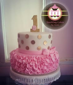 a birthday cake with pink and gold ruffles on the bottom is for a one year old