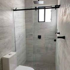 a white toilet sitting next to a walk in shower