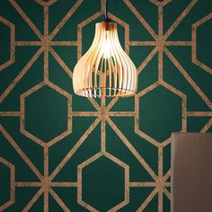 a lamp hanging from the ceiling in front of a green wall with geometric designs on it