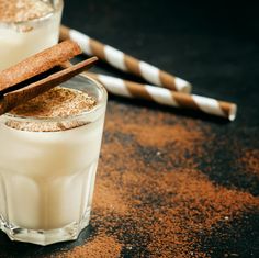 two glasses filled with milk and cinnamon sticks