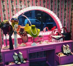 there is a pink vanity with shoes and bags on it in front of a mirror