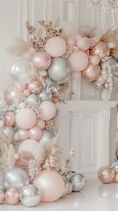 a bunch of balloons that are in the air next to some flowers and feathers on a table