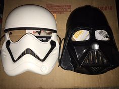 two star wars helmets sitting on top of a cardboard box, one with the word trooper written on it