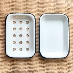 two black and white dishes sitting on top of a cloth covered table next to each other