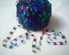 a multicolored ball of yarn next to a pair of lanyards on a white surface