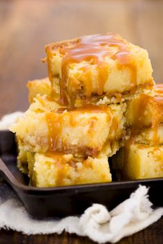 several pieces of cake sitting on top of a black plate covered in caramel sauce