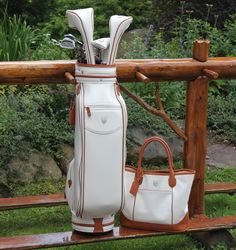 two golf clubs and a white bag on a wooden bench