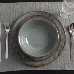 a place setting with silverware and utensils on a gray table cloth,