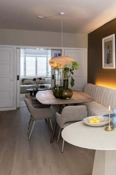 a dining room table with two chairs and a vase on top of it in front of a couch