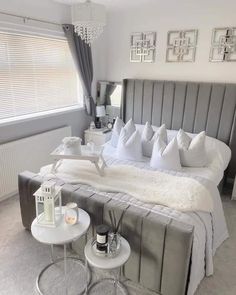 a large bed sitting in a bedroom next to a window with pictures on the wall