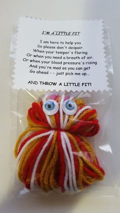 an orange and white yarn ball with eyes on it's side in a package