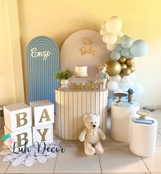 a baby shower with balloons, cake and teddy bear sitting on the floor next to it