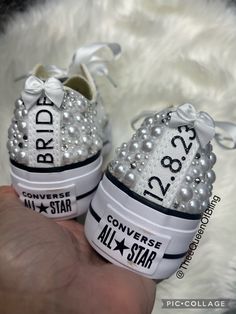 someone is holding their converse all star wedding shoes with pearls on the bottom and bows at the top