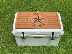 a cooler sitting in the grass with a texas state emblem on it's lid