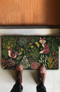 someone's feet are standing on a door mat