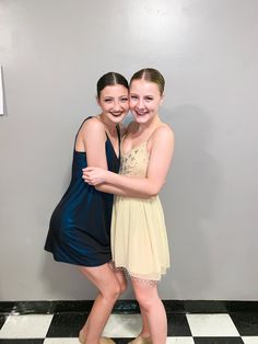 two young women standing next to each other in front of a white and black checkered floor