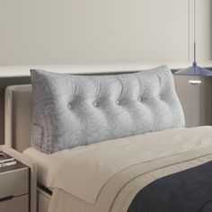 a bed with a white and blue comforter on top of it next to a night stand