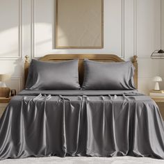 a bed with grey sheets and pillows in a room