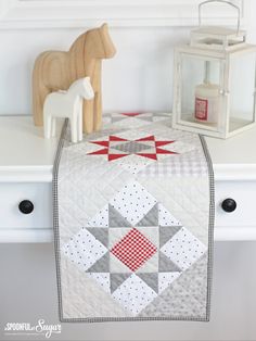 a quilted table runner sitting on top of a white dresser next to a wooden toy horse