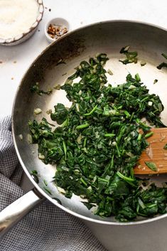 spinach being cooked in a pan with a wooden spoon