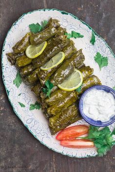 stuffed grape leaves on a plate with yogurt and garnishes for dipping