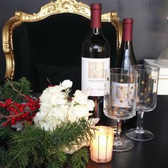 two bottles of wine sitting on top of a wooden table next to candles and flowers