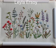 embroidered flowers and bees on a white board with the words, letta ersy