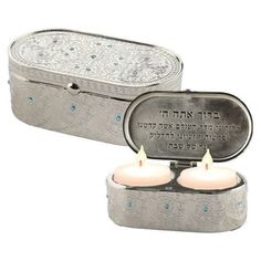 two lit candles in a metal box with an inscription on the front and back side