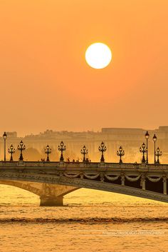 the sun is setting over a bridge in paris