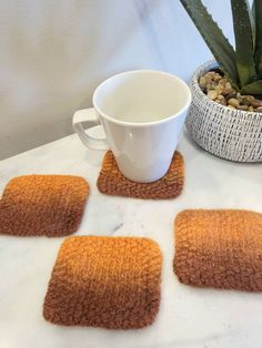 four brown rugs on a table with a cup and plant in the corner next to them