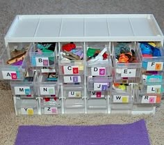 a plastic bin filled with lots of different types of letters and numbers next to a purple rug