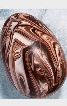 a marbled bowl is sitting on a blue surface and looks like it has been swirled with chocolate