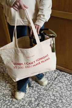 a person holding a tote bag that says sorry i can't tonight, my dog and i have plans