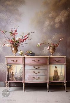 two vases with flowers on top of a dresser in front of a wall mural