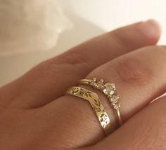 a woman's hand with two gold rings on top of her finger and the other ring