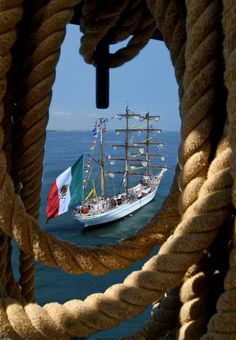 a large boat sailing in the ocean through a roped porthole with an italian flag on it's mast