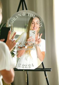 a woman taking a selfie with her cell phone in front of a large mirror