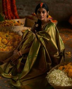 a woman sitting on the ground next to baskets filled with food