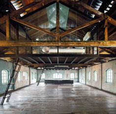 the inside of an old warehouse with exposed ceilings and windows, ladders leading up to it